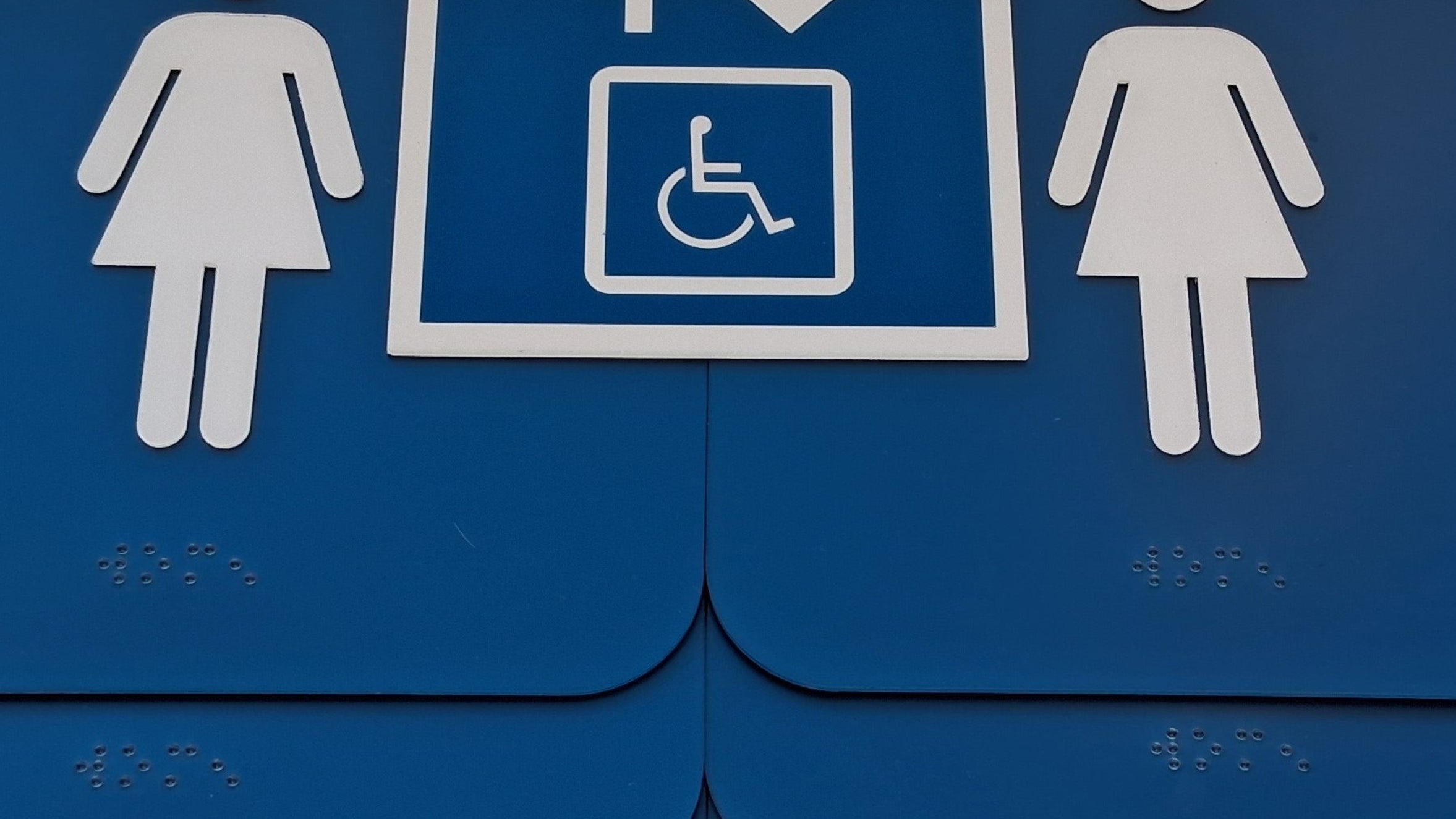Custom made braille ADA signs with accessibility icon and female figure symbols on a blue background