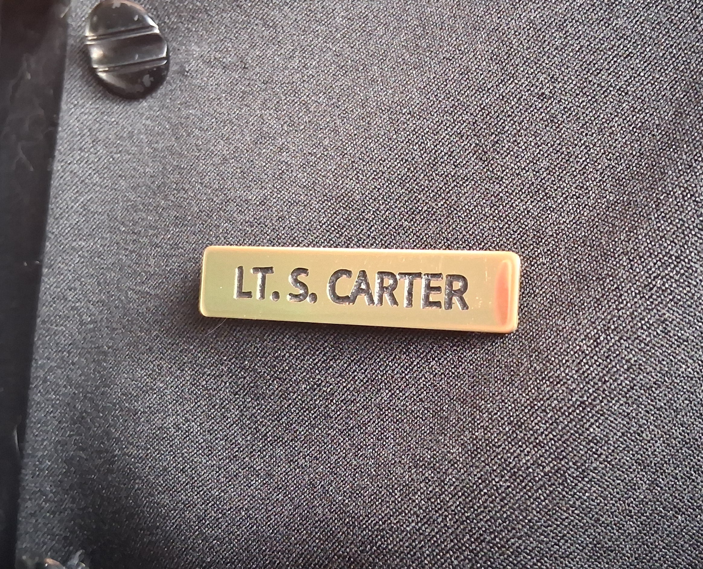 Custom engraved Brass colour filled name tag on a dark fabric background