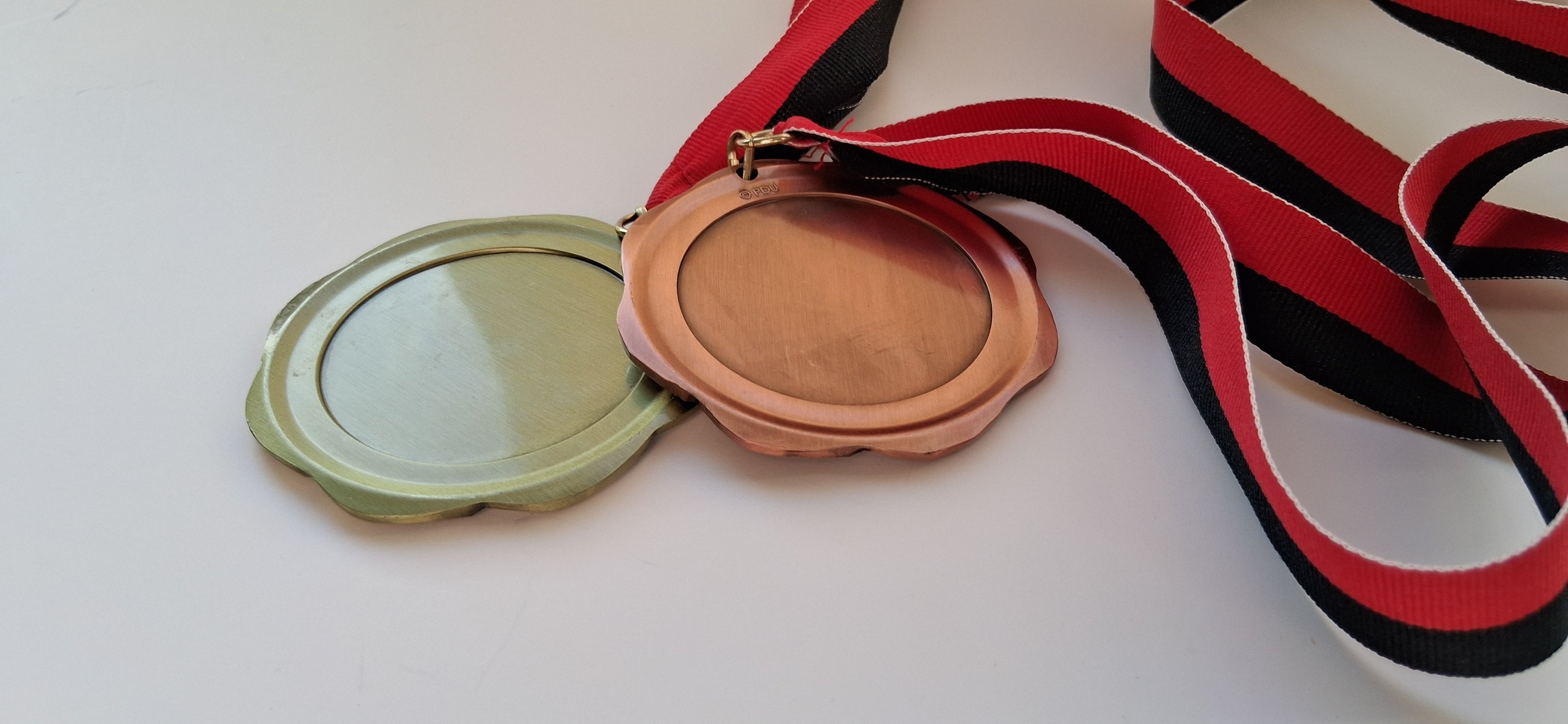 Two medals, one gold and one bronze, on ribbons with a red and black stripe.