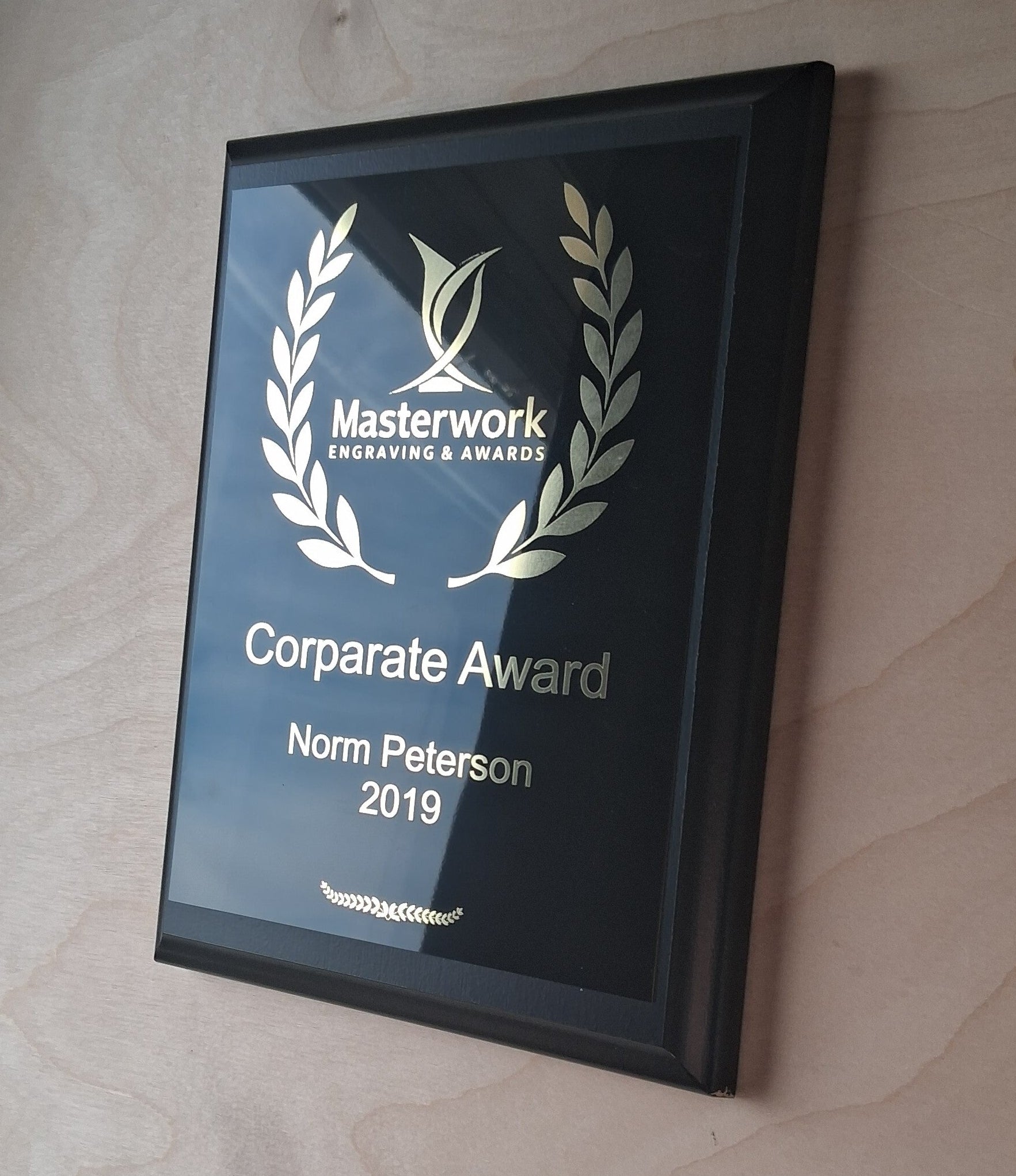 Custom engraved corporate award with 'Masterwork Engraving & Awards' on a wooden surface