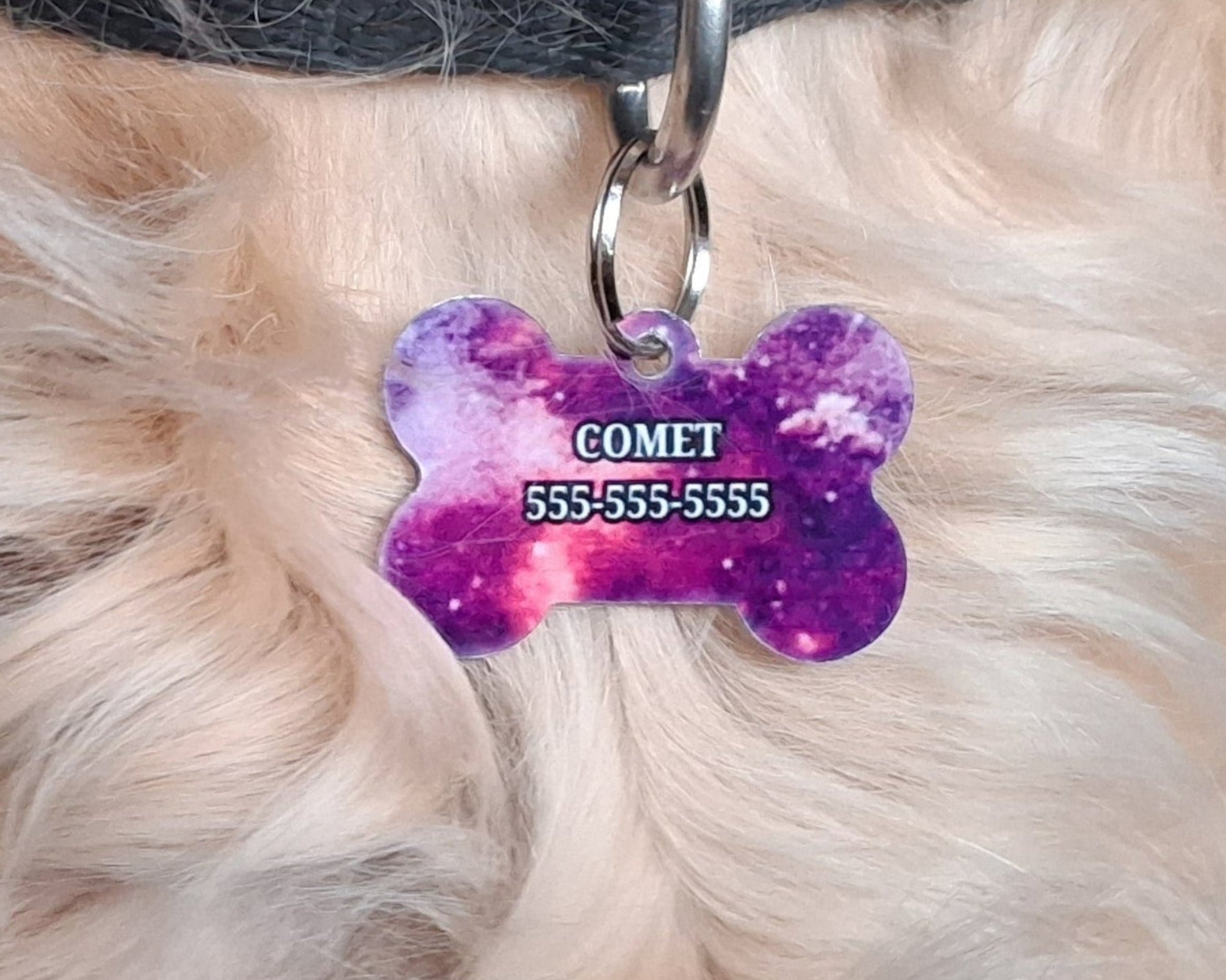 Bone shaped, custom colour printed pet tag with 'COMET' and phone number on a fluffy white fur background